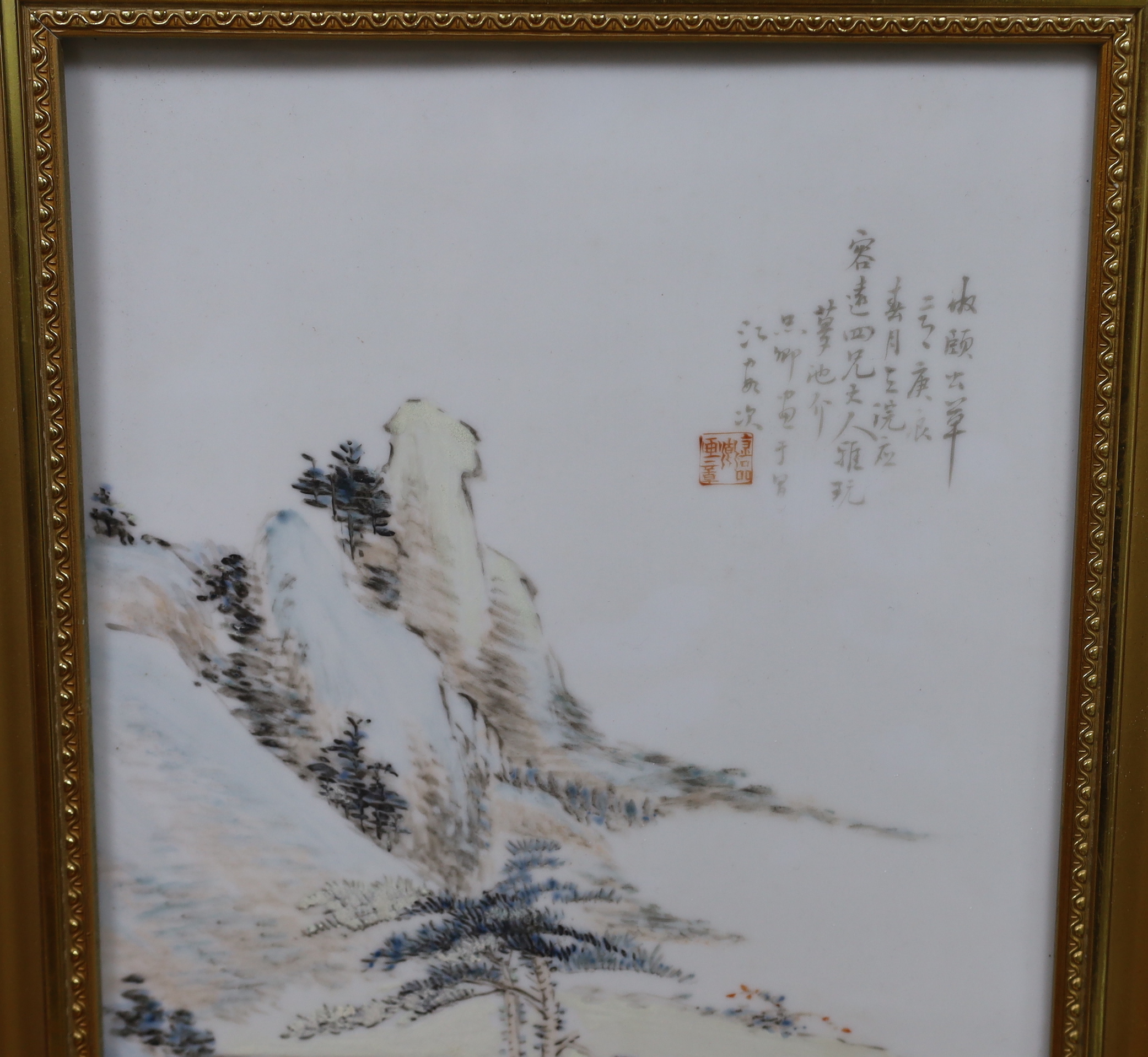 A Chinese enamelled porcelain plaque, decorated with a mountainous landscape and calligraphy, framed, overall 47cm x 34cm